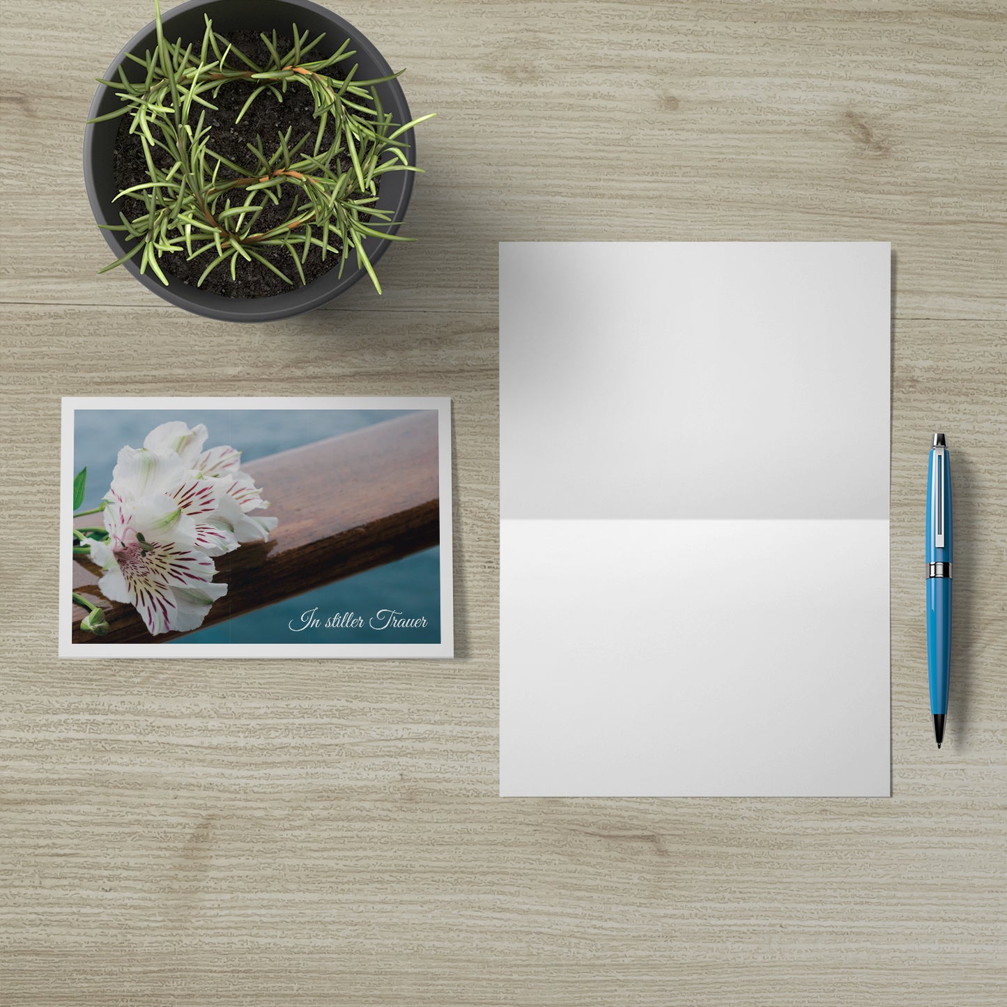 Hochwertige nachhaltige Trauerkarten mit floralem Design, Klappkarte mit Umschlag auf hellem Holztisch.
