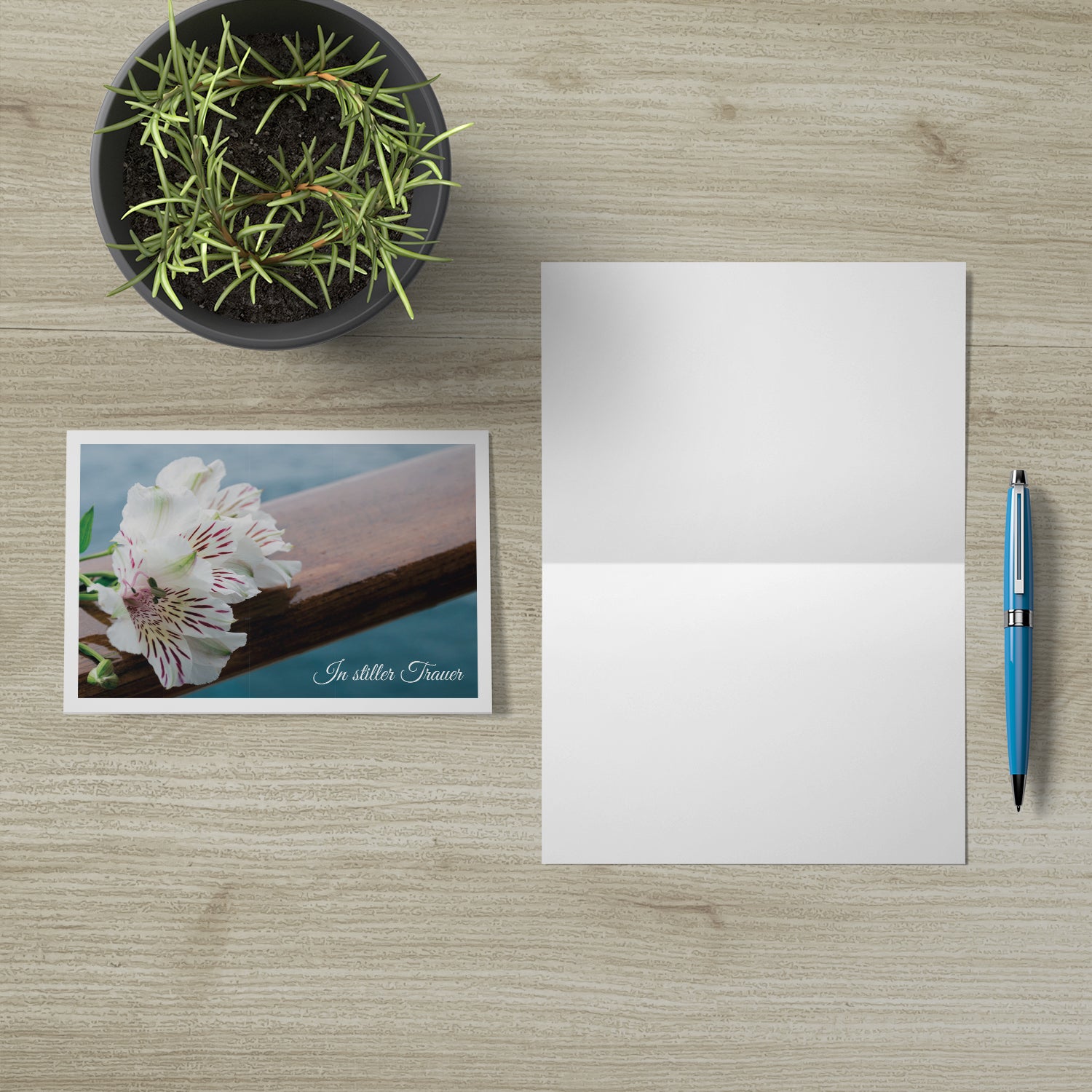 Hochwertige nachhaltige Trauerkarten mit floralem Design, Klappkarte mit Umschlag auf hellem Holztisch.