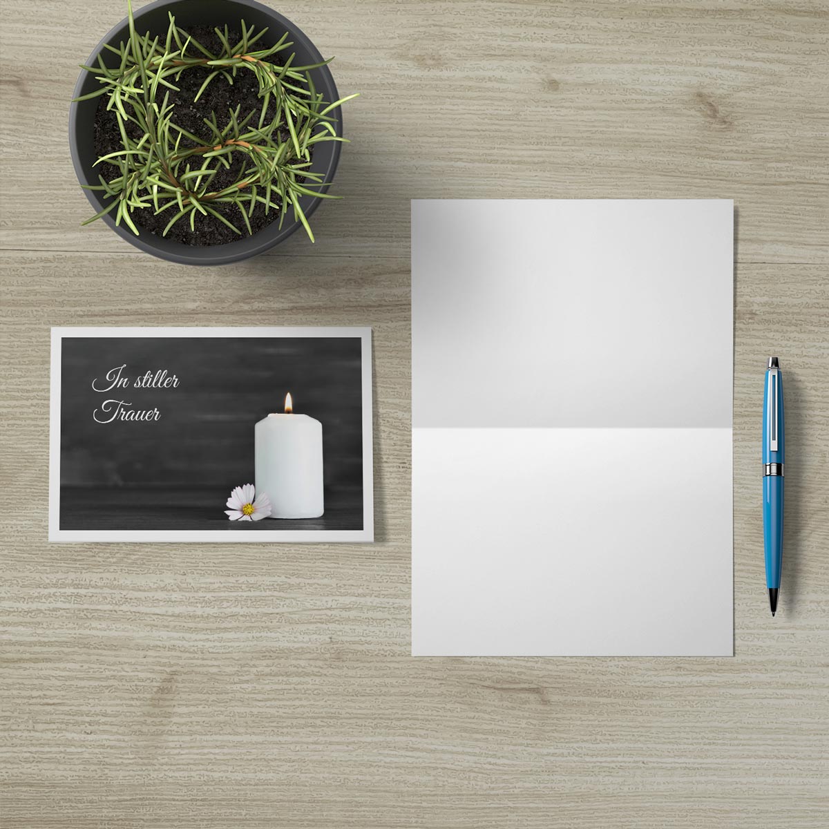 Hochwertige nachhaltige Trauerkarte mit Kerze und schlichter Schrift, Klappkarte mit Umschlag und Stift auf Holztisch.