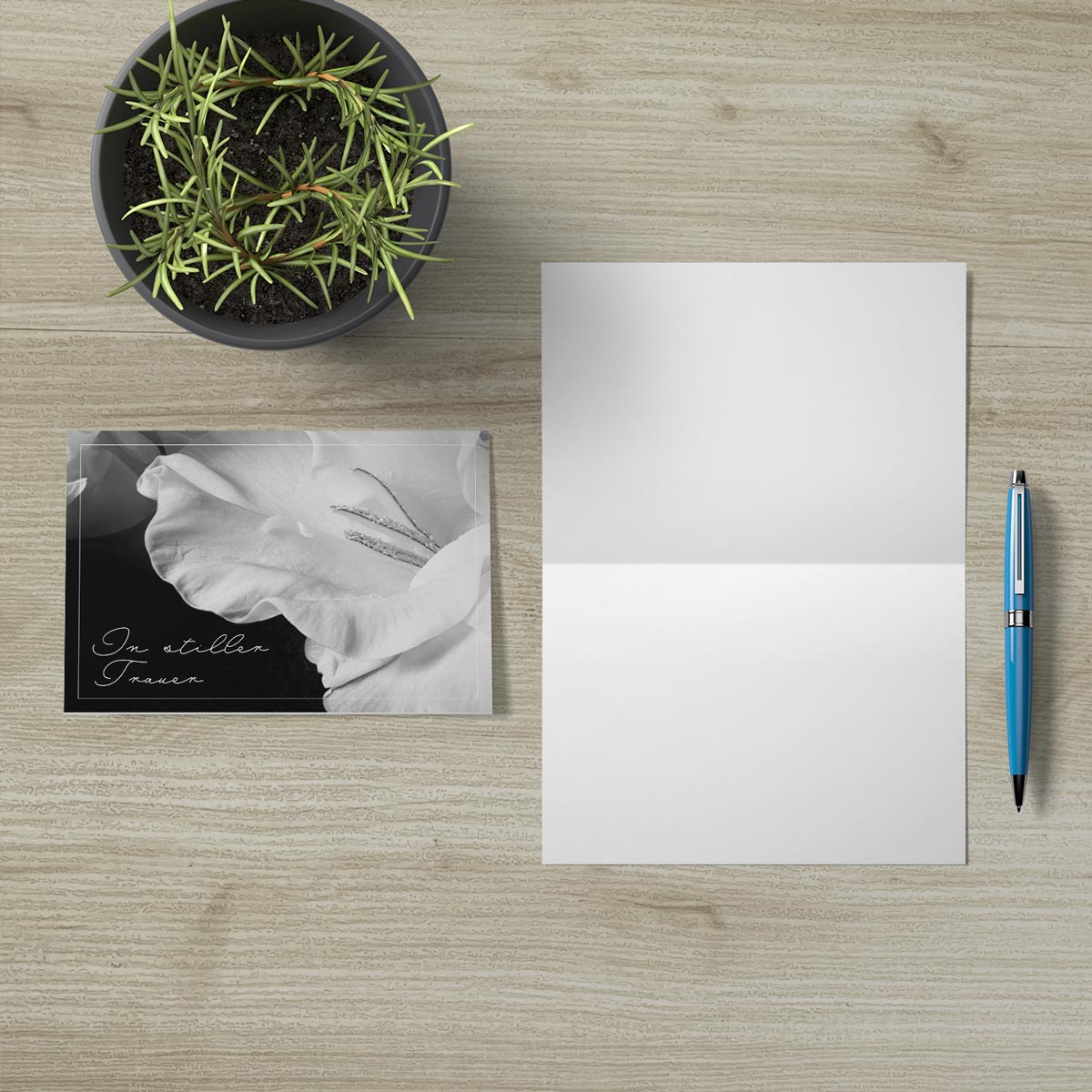 Hochwertige nachhaltige Trauerkarte mit schwarz-weiß Rosen-Design, offen mit Umschlag und blauer Kugelschreiber.