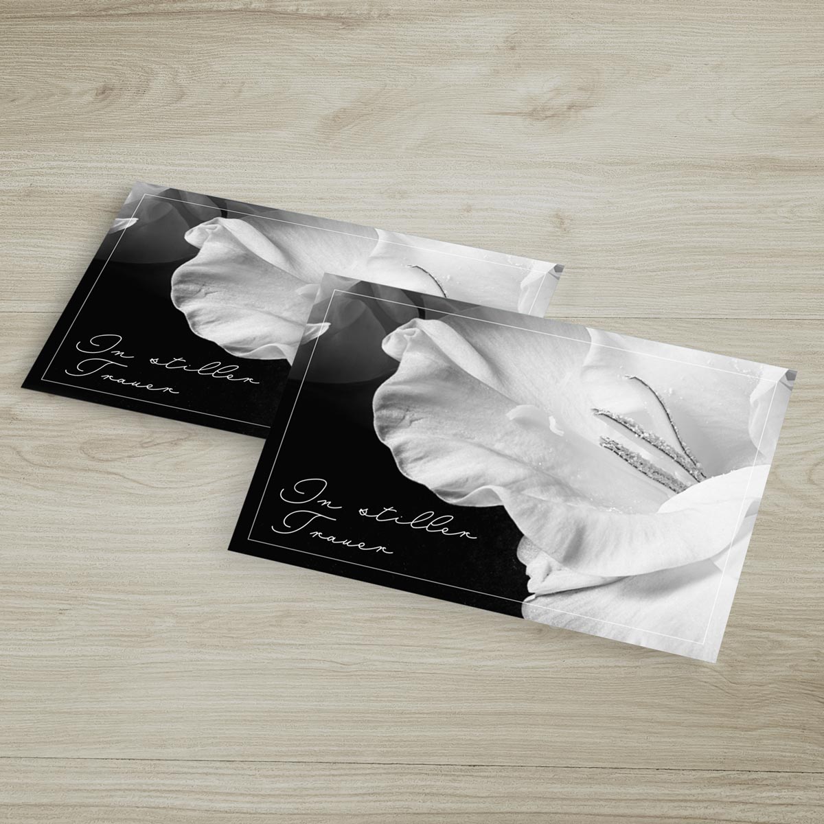 Zwei hochwertige, nachhaltig gestaltete Trauerkarten mit Blumendesign und einfühlsamem Spruch auf schwarzem Hintergrund.